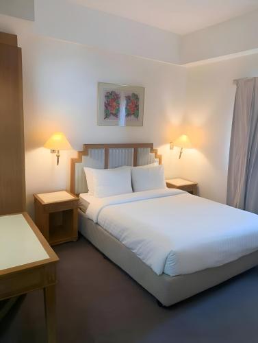 a bedroom with a large white bed with two tables at 2BR Seaview Condo with Balcony, Riviera Bay Resort Melaka in Malacca