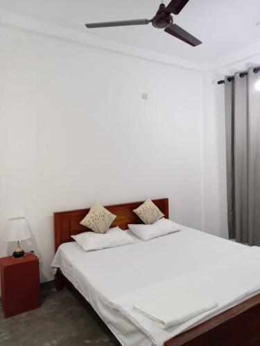 a bedroom with a white bed with a ceiling fan at The Grand Villa Malabe in Malabe