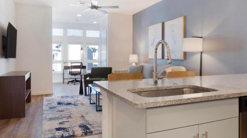 a kitchen with a sink and a living room at Landing Stylish 2BD Gym Pool in Colorado Springs