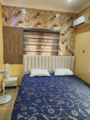 a bedroom with a large bed with a blue bedspread at The Oasis in Ilorin