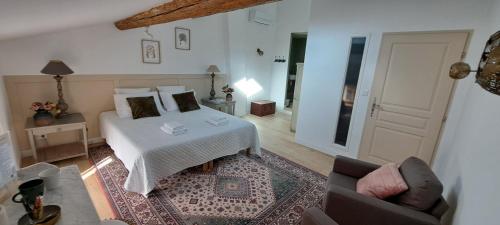 a bedroom with a white bed and a living room at Le MAS CLEMENTINE in Puisserguier