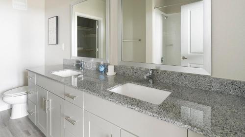 a bathroom with two sinks and a large mirror at Landing Incredible 1BD Pool Gym in Katy