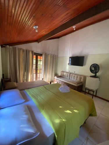a bedroom with a green bed and a couch at Maria Candida Hospedaria in Areias