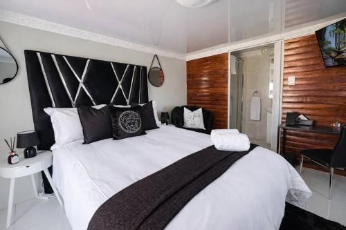 a bedroom with a large white bed with a black headboard at Elite Luxe Cabin Suite in Welkom