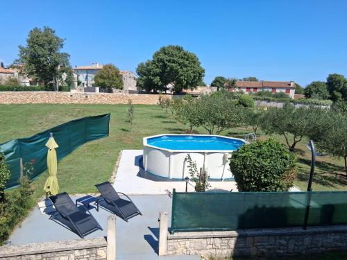 a patio with chairs and a pool in a yard at Apartment Glavani with Pool in Barban