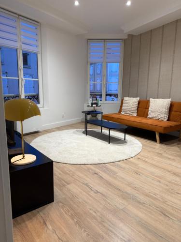a living room with a couch and a table at L'écrin orange, Wifi et parking gratuit in Chalons en Champagne