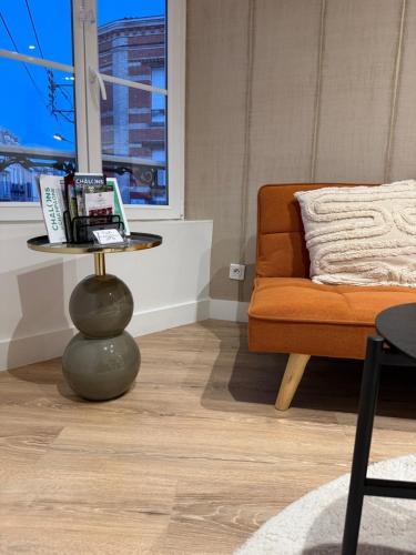 a living room with a table and a couch at L'écrin orange, Wifi et parking gratuit in Chalons en Champagne