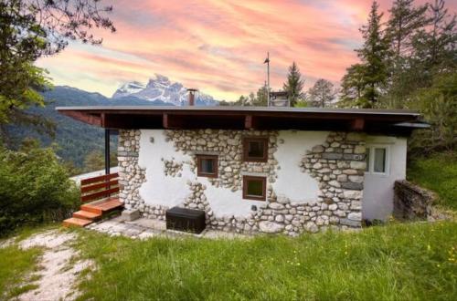 a stone house with a mountain in the background at Modernist Chalet in Borca di Cadore
