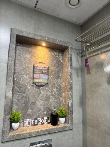 a sign on a wall in a bathroom with two plants at Landin2home studios in New Delhi