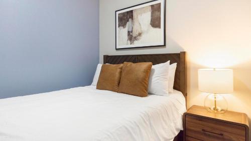 a bedroom with a bed with white sheets and a lamp at Landing Apartments - 2720 S Federal in Englewood