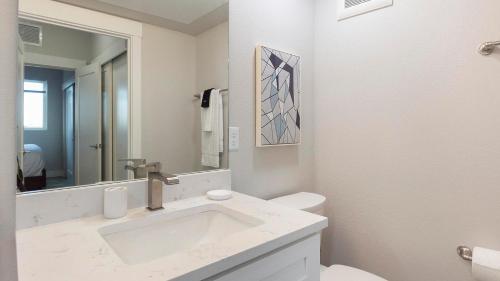 a white bathroom with a sink and a mirror at Landing Apartments - 2720 S Federal in Englewood