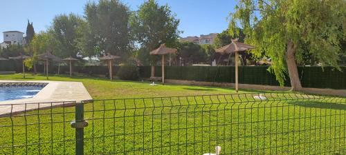 a fence with umbrellas and a pool in a park at Apartamento acogedor El portil in El Portil