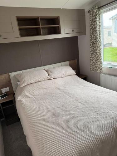 a bedroom with a large white bed with a window at Paws A While in Mainsriddle