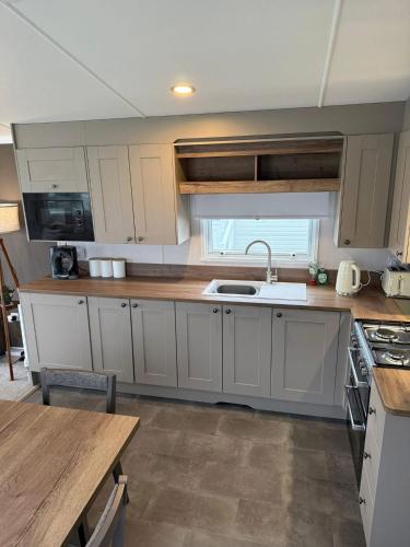 a kitchen with white cabinets and a sink at Paws A While in Mainsriddle