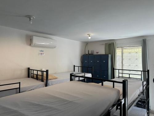 a room with three beds and a window at Hostel Casinha Tropical in Rio de Janeiro