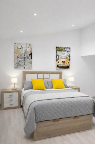 a bedroom with a bed with two yellow pillows at Casa Vidán completa Santiago Rural in Santiago de Compostela