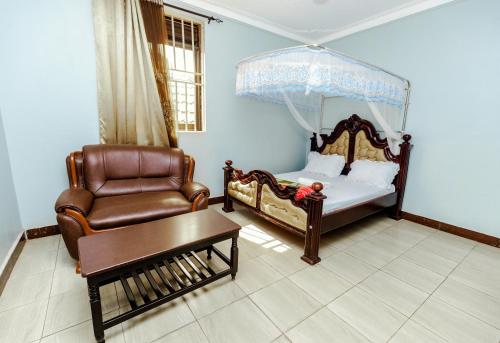 a bedroom with a bed and a chair and a table at Hulcity silver hotel in Kyebando