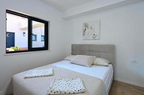 a white bedroom with a bed with a window at Apartman Roso in Orebić