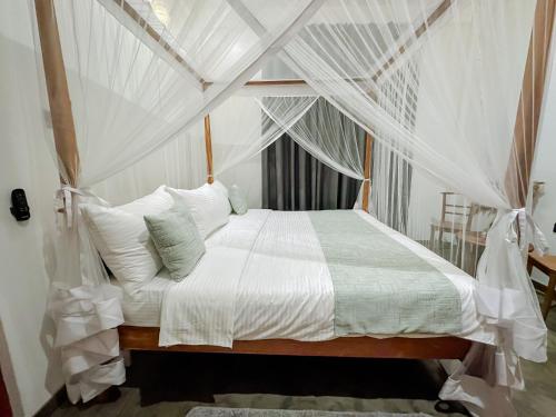 a bedroom with a white bed with mosquito netting at Lagoon View Mawella Villa in Tangalle