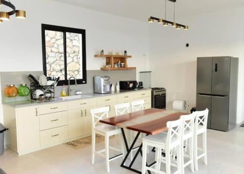 a kitchen with a wooden table and a refrigerator at ממלכת החלומות - וילה מהממת עם בריכה פרטית מחוממת מקורה ונוף מהמם in ‘Ein el Asad
