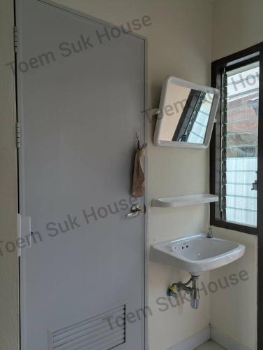 a bathroom with a sink and a mirror next to a door at เติมสุขเฮาส์ Toem Suk House in Ban Bang Luk