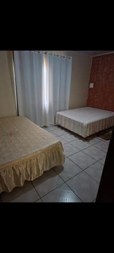 a room with two beds and a tiled floor at Sitio4meninos in Pinheiral