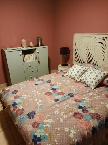 a bedroom with a bed with a floral comforter at Chambre cosy avec piscine in Saint-Benoît