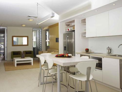 a kitchen and living room with a table and chairs at Grand Mercure Apartments Magnetic Island in Nelly Bay