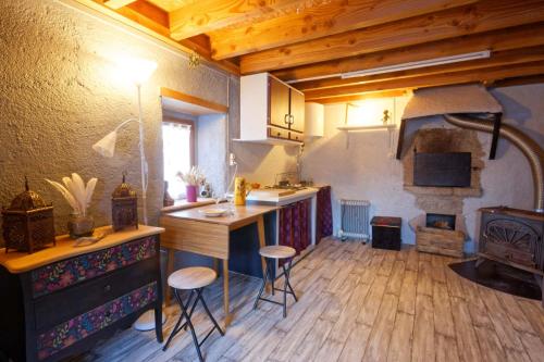 a kitchen with a counter and stools in a room at Maisonnette cocooning, ancien four à pain in Saint-Éloy-la-Glacière