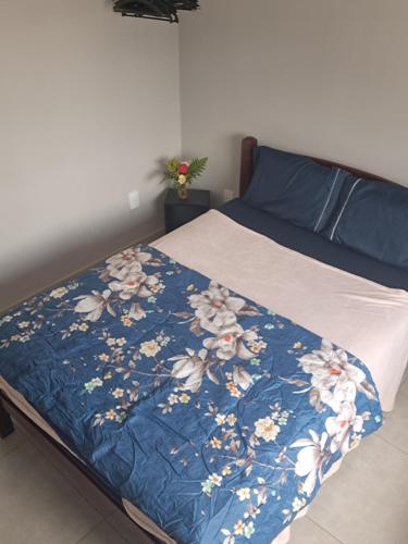 a bed with a blue blanket with flowers on it at Casa com piscina Espaço teddy cakes in Campinas