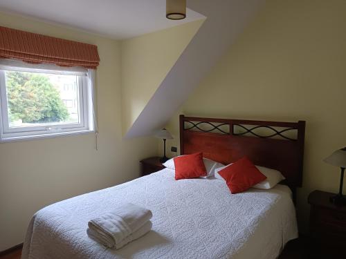 a bedroom with a bed with red and white pillows at Apart Hotel Croacia in Puerto Montt