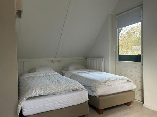 two twin beds in a room with a window at Natuurhuisje Even Niets in Zelhem