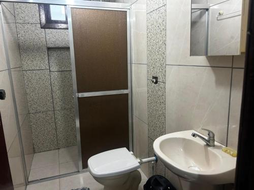 a bathroom with a shower and a toilet and a sink at Casa da vó in Jaguaruna