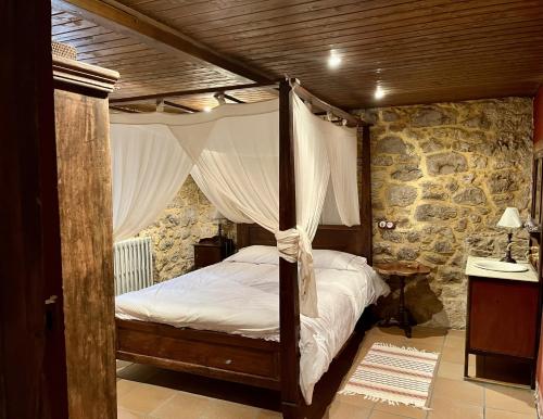 a bedroom with a canopy bed and a stone wall at La casa de Chipi Lacavada in La Cavada