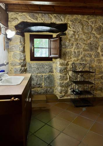 a bathroom with a sink and a stone wall at La casa de Chipi Lacavada in La Cavada