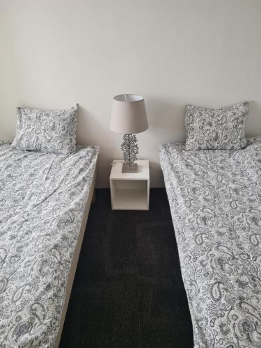 ein Schlafzimmer mit zwei Betten und einem Tisch mit Lampe in der Unterkunft Suite 3 in Frederikshavn