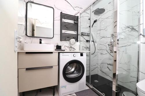 a bathroom with a washing machine and a shower at La Cosy House in Courcouronnes