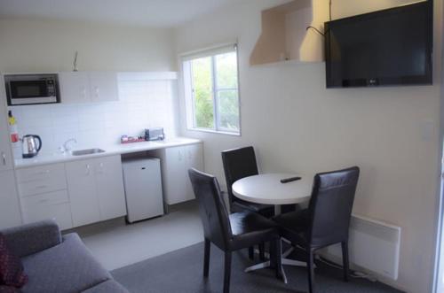 a living room with a table and chairs and a kitchen at Wellington 747 Motel in Wellington