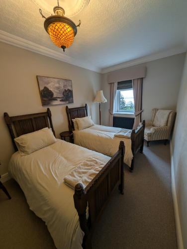 a bedroom with two beds and a chair and a chandelier at Gower view in Burry Port