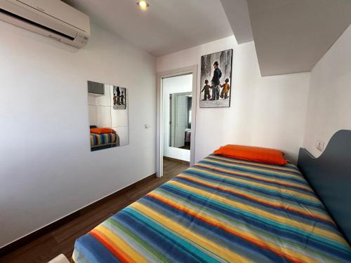 a bedroom with a bed with a colorful striped blanket at TuttiFruttiaApt in Nerja