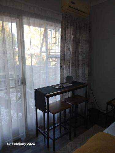 a small table in a room with a window at Aroha Guest Apartment in Roodepoort