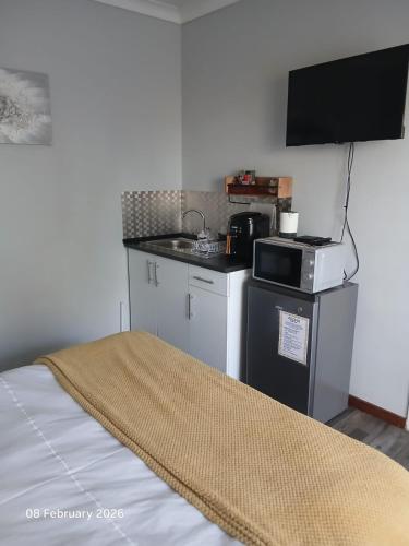 a small kitchen with a stove and a microwave at Aroha Guest Apartment in Roodepoort