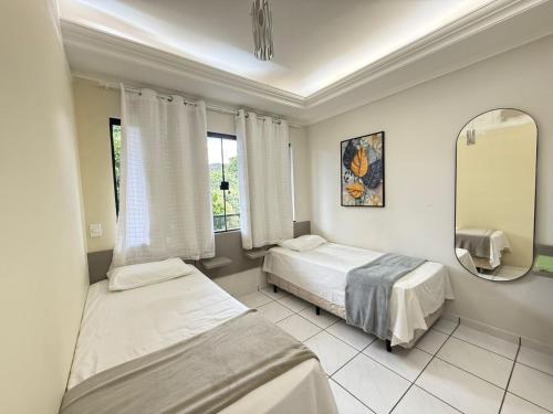 a bedroom with two beds and a mirror at Pousada DONA LÍDIA in Campo Mourão