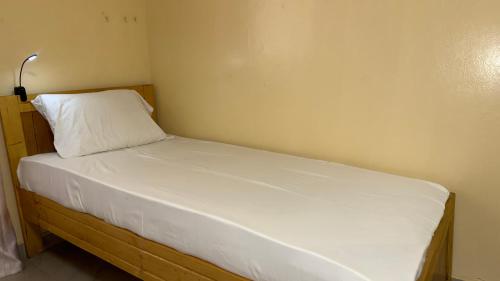 a small bed with a white pillow in a room at 1 lit en dortoir partagé - Résidences PRIMIS Thiès in Thies