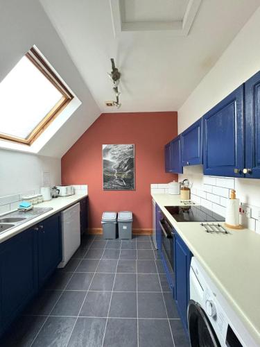 a kitchen with blue cabinets and a red wall at The Malt House, Portree in Portree