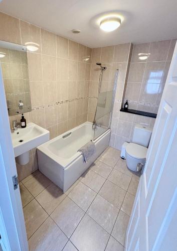 a bathroom with a tub and a sink and a toilet at The Stables B&B @ Pear Tree Cottage in Winslow
