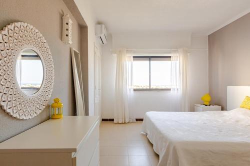 a white bedroom with a bed and a mirror at Sea House Apartment - Private Condo with 4 Pools, Jacuzzi & Tennis Court in Albufeira