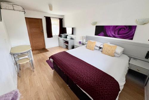 a bedroom with a large bed with a purple blanket at The Stables B&B @ Pear Tree Cottage in Winslow