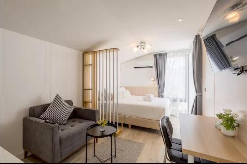 a room with a couch and a bed and a table at Ningle Place Hotel Pathumthani in Ban Pak Khlong Si