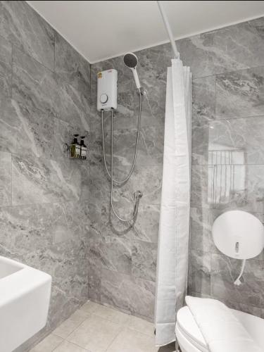 a bathroom with a shower and a toilet and a sink at Ningle Place Hotel Pathumthani in Ban Pak Khlong Si